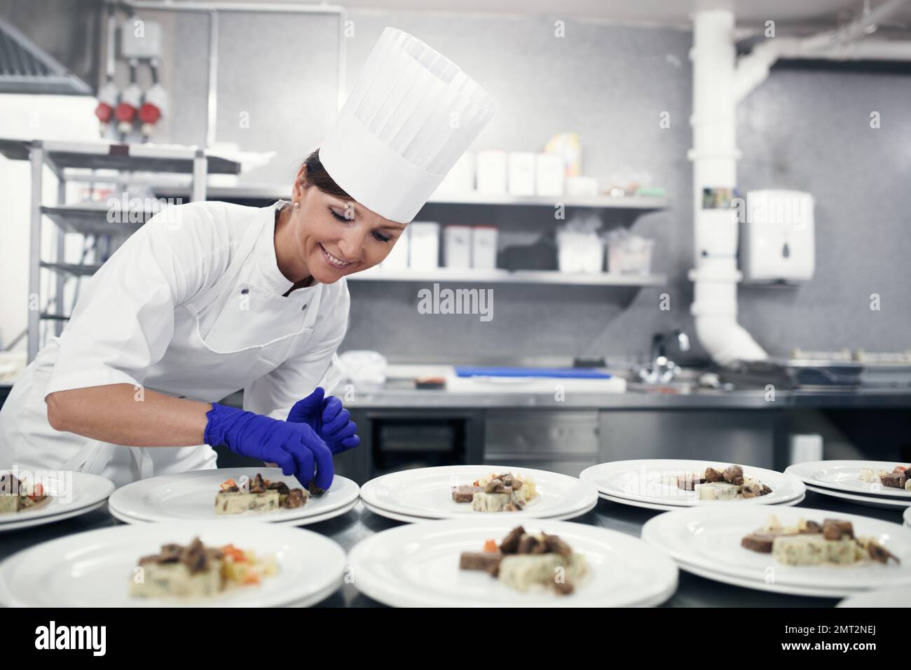 Fare un pasto in arte. Uno chef che prepara cibo per un servizio di pasto in una cucina professionale. Foto Stock
