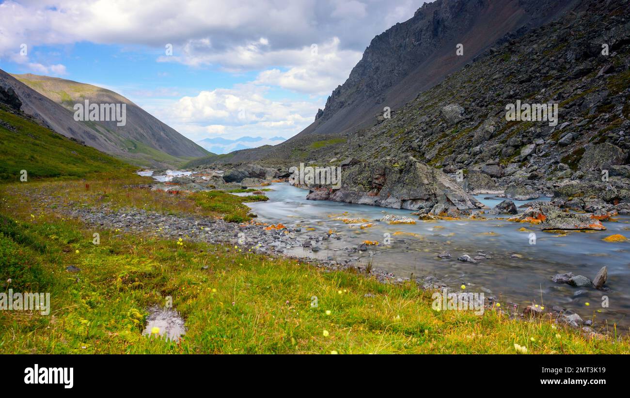 L'acqua turchese del fiume Karakabak scorre tra le pietre con muschio arancione nelle montagne Altai. Foto Stock