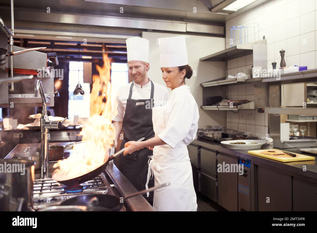 Cucinare con il fuoco. chef che si divertire in una cucina ristorante. Foto Stock