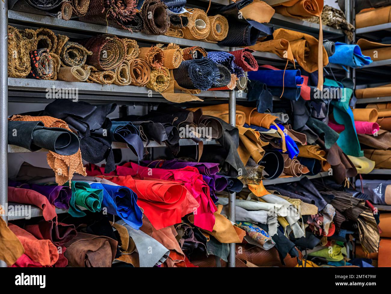 Rotoli colorati di pelle e tessuto su scaffali sul retro di una tradizionale bottega e studio artigianale di cuoio a Centro storico, Firenze Foto Stock