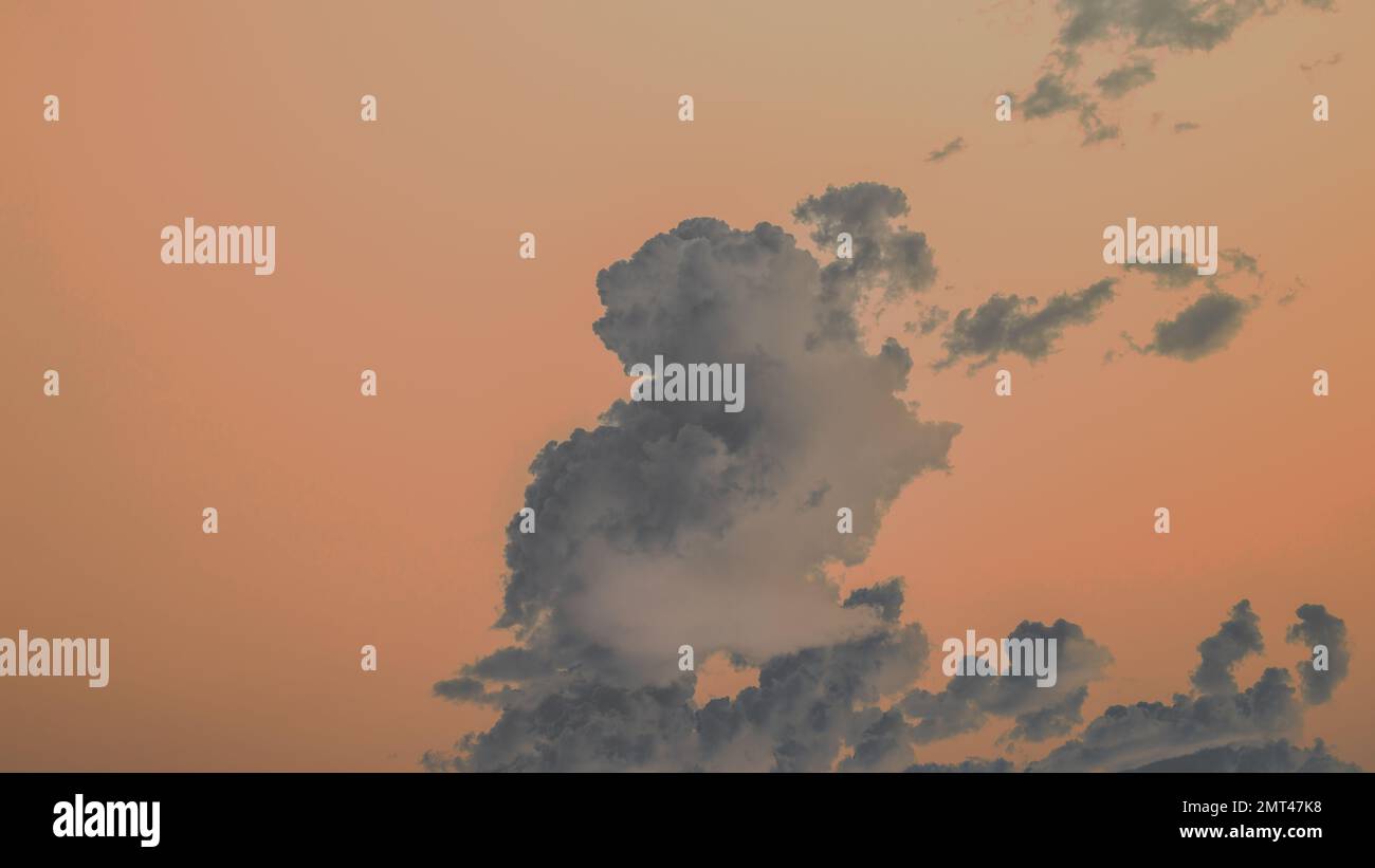 Una fotografia astratta di nuvole di cumuli contro un cielo arancione brillante. Foto Stock