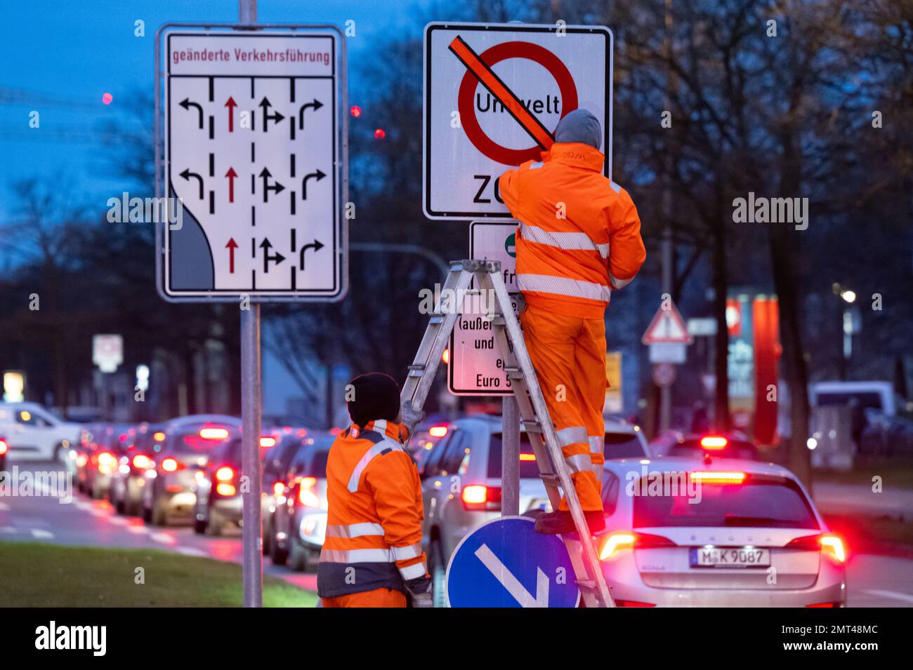 Monaco, Germania. 01st Feb, 2023. I lavoratori rimuovono una striscia adesiva rossa da un cartello con la scritta "Environment zone" (zona ambiente) e "Diesel (eccetto traffico di consegna e residenti) solo da Euro 5/V". A partire dal 01 febbraio 2023, un divieto di guida si applicherà ai veicoli diesel con gli standard Euro 4/IV e le norme sulle emissioni peggiori nella zona ambientale estesa intorno al Mittlerer Ring. Il traffico delle consegne e i residenti sono esentati dal divieto di guida del gasolio per mezzo di segnaletica. Credit: Sven Hoppe/dpa/Alamy Live News Foto Stock