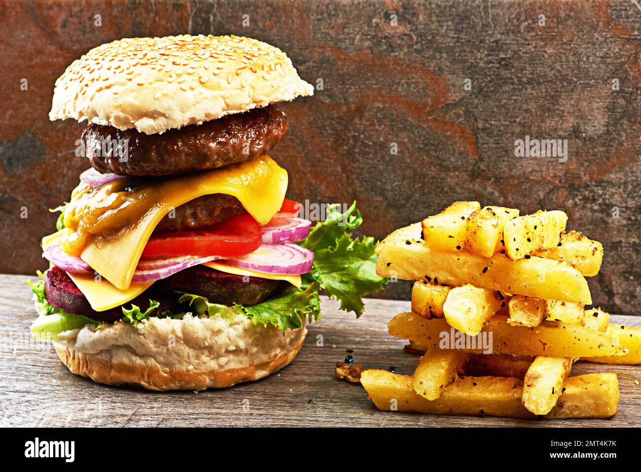 Le risate sono le più brillanti dove il cibo è meglio. un delizioso hamburger a tre piani con patatine fritte. Foto Stock