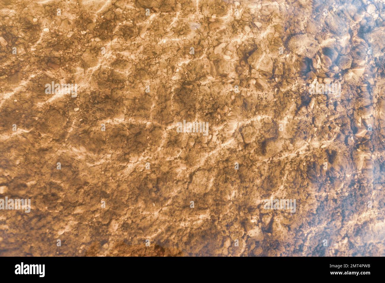 Sfondo astratto e naturale nei toni scuri della borgogna. Foto di una superficie trasparente dell'acqua e delle onde con pietre sul fondo sabbioso Foto Stock