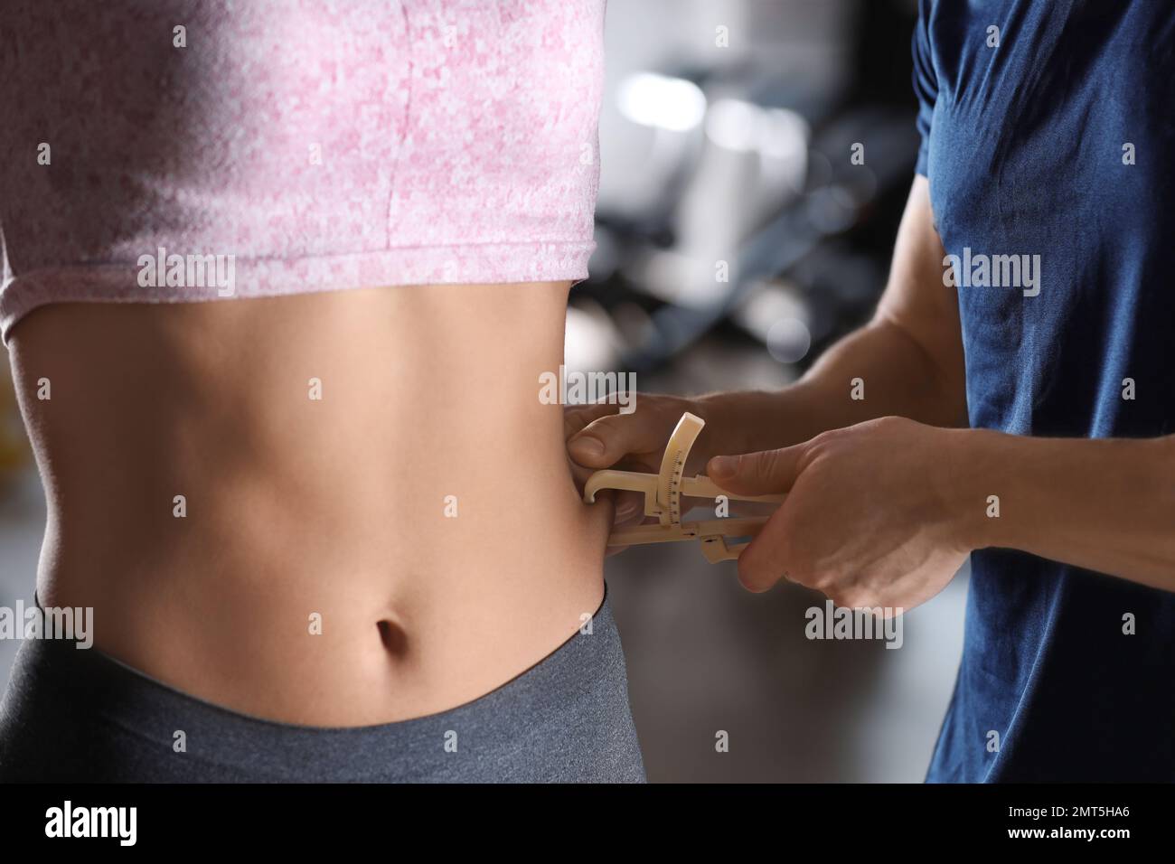 Nutrizionista che misura lo strato grasso del corpo della donna con calibro interno, primo piano Foto Stock