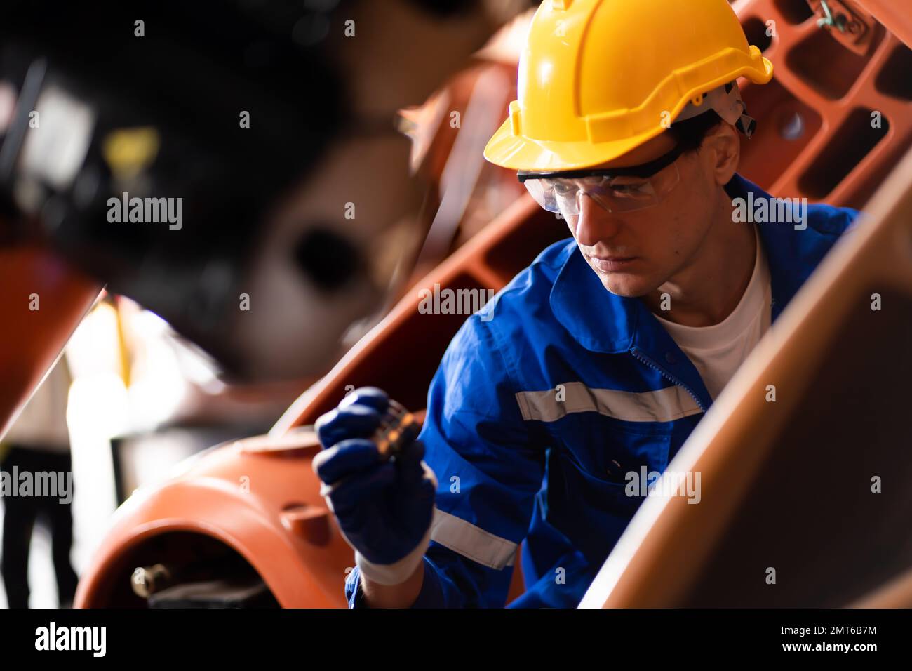 Un team di ingegneri maschili e femminili si riunisce per ispezionare i robot di saldatura dell'acciaio controllati dal computer. Pianificare le prove e l'installazione per l'uso. Foto Stock