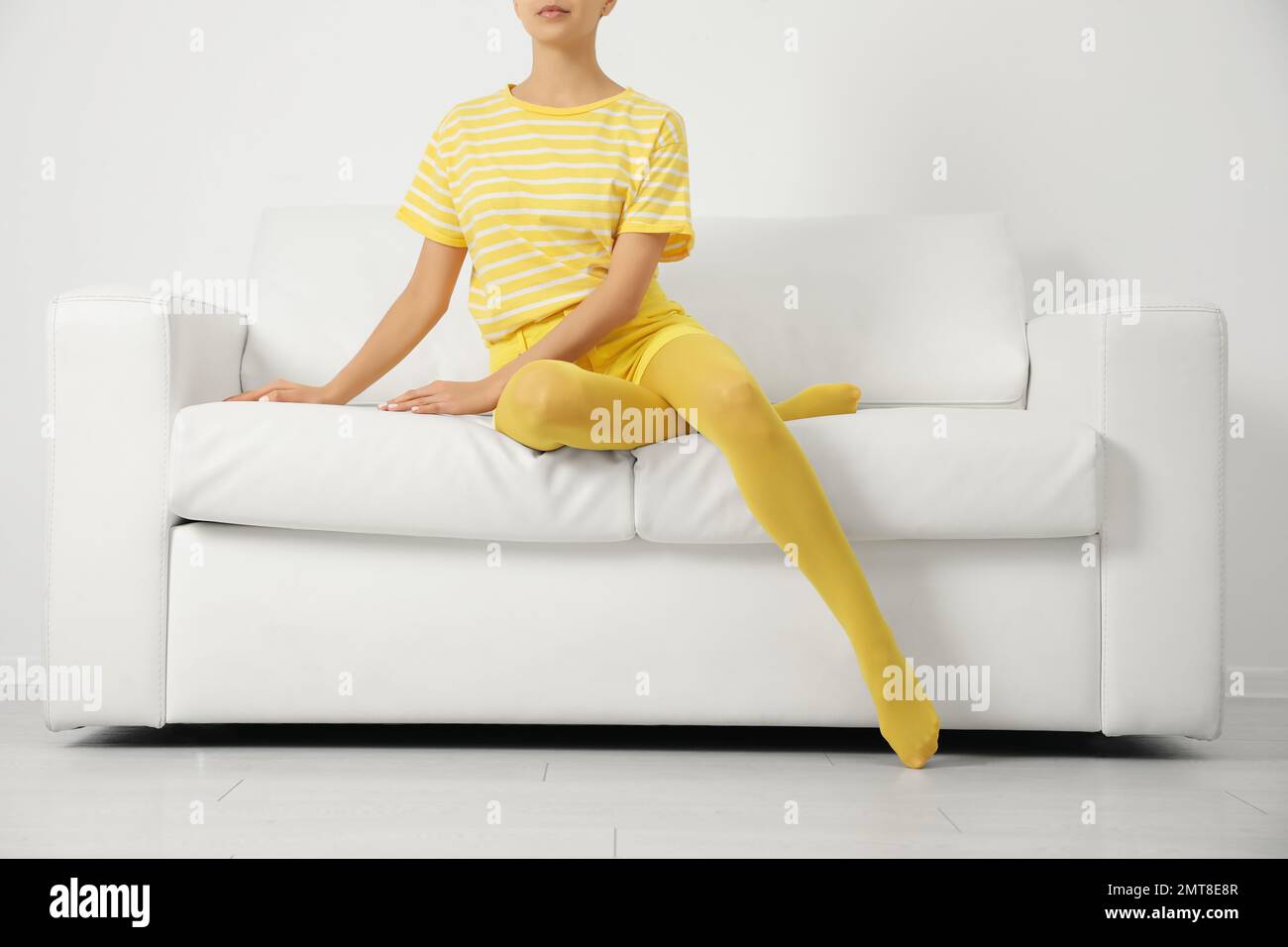 Donna che indossa collant gialli seduti sul divano interno, guardaroba Foto  stock - Alamy