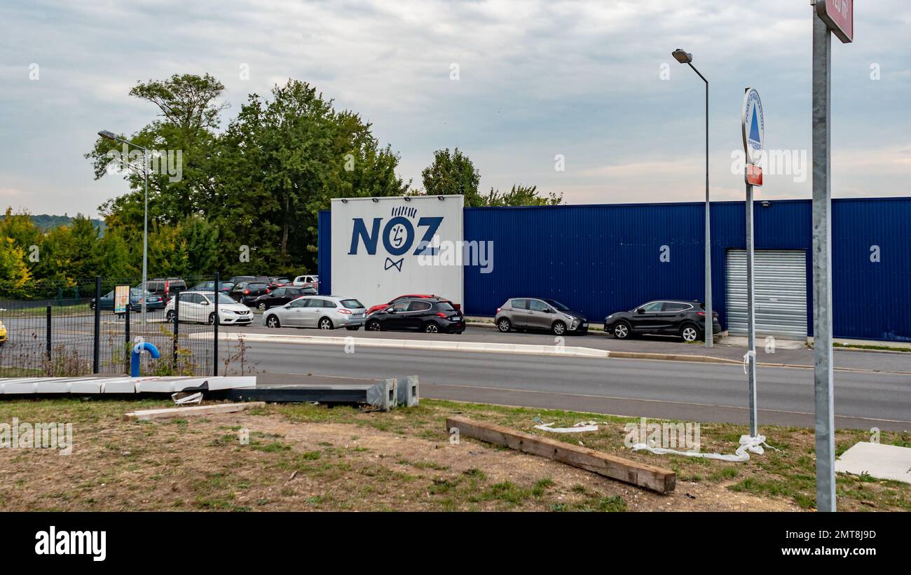 Una vista sulla strada con auto nella città di Coulommiers e il logo di NOZ negozio sullo sfondo in Francia Foto Stock
