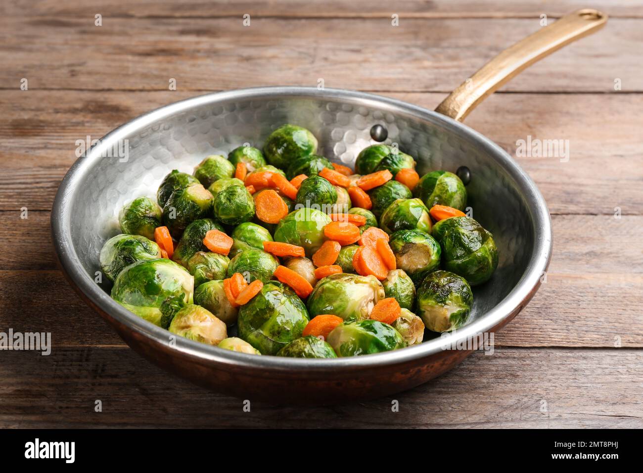 Germogli di Bruxelles arrostiti con carota in padella su tavolo di legno Foto Stock