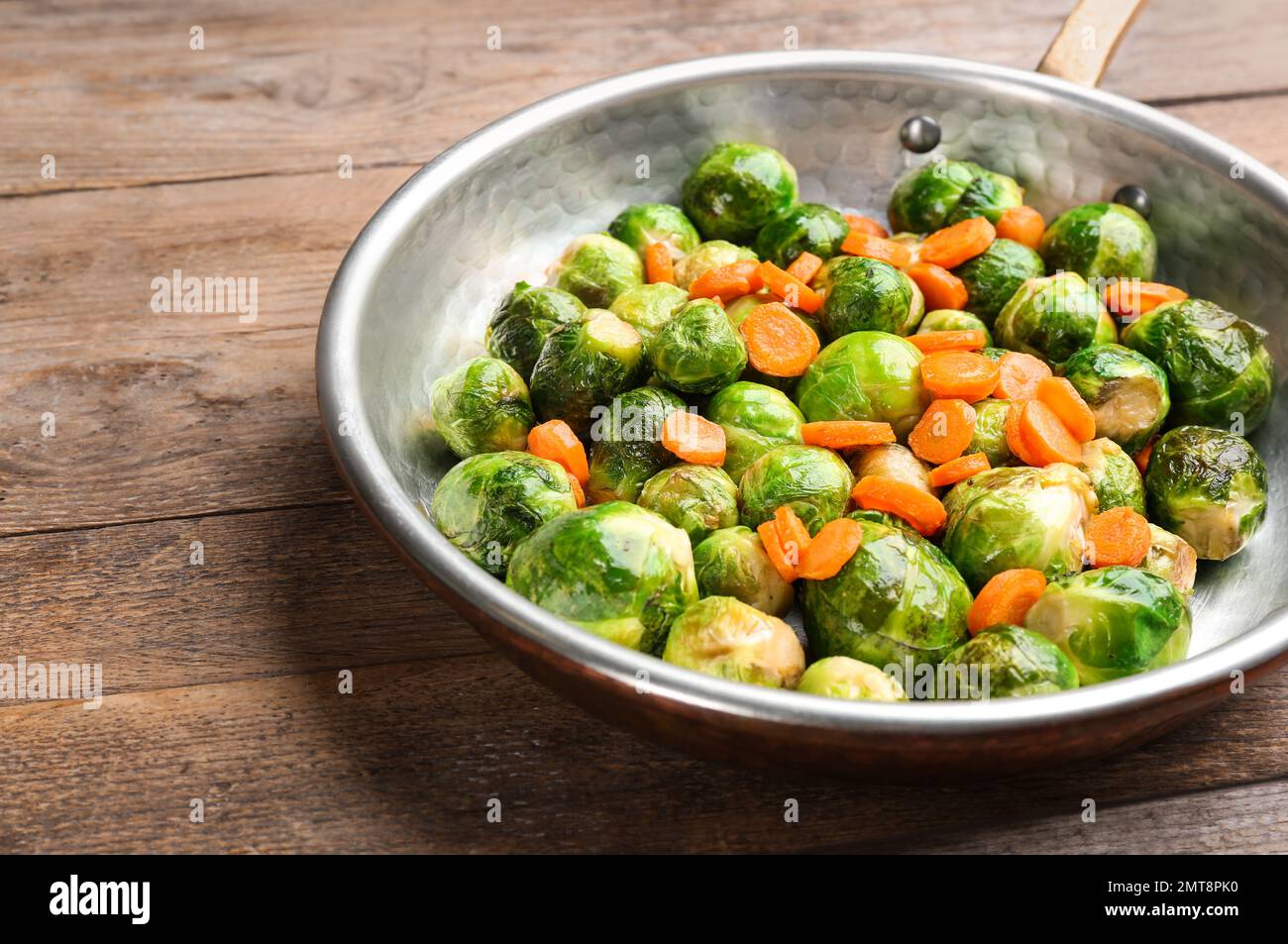 Germogli di Bruxelles arrostiti con carota in padella su tavolo di legno Foto Stock