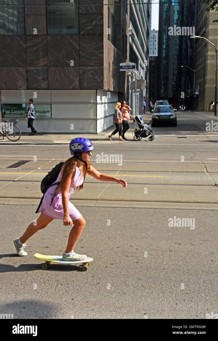 Una giovane donna cavalca su skate board per strada Foto Stock