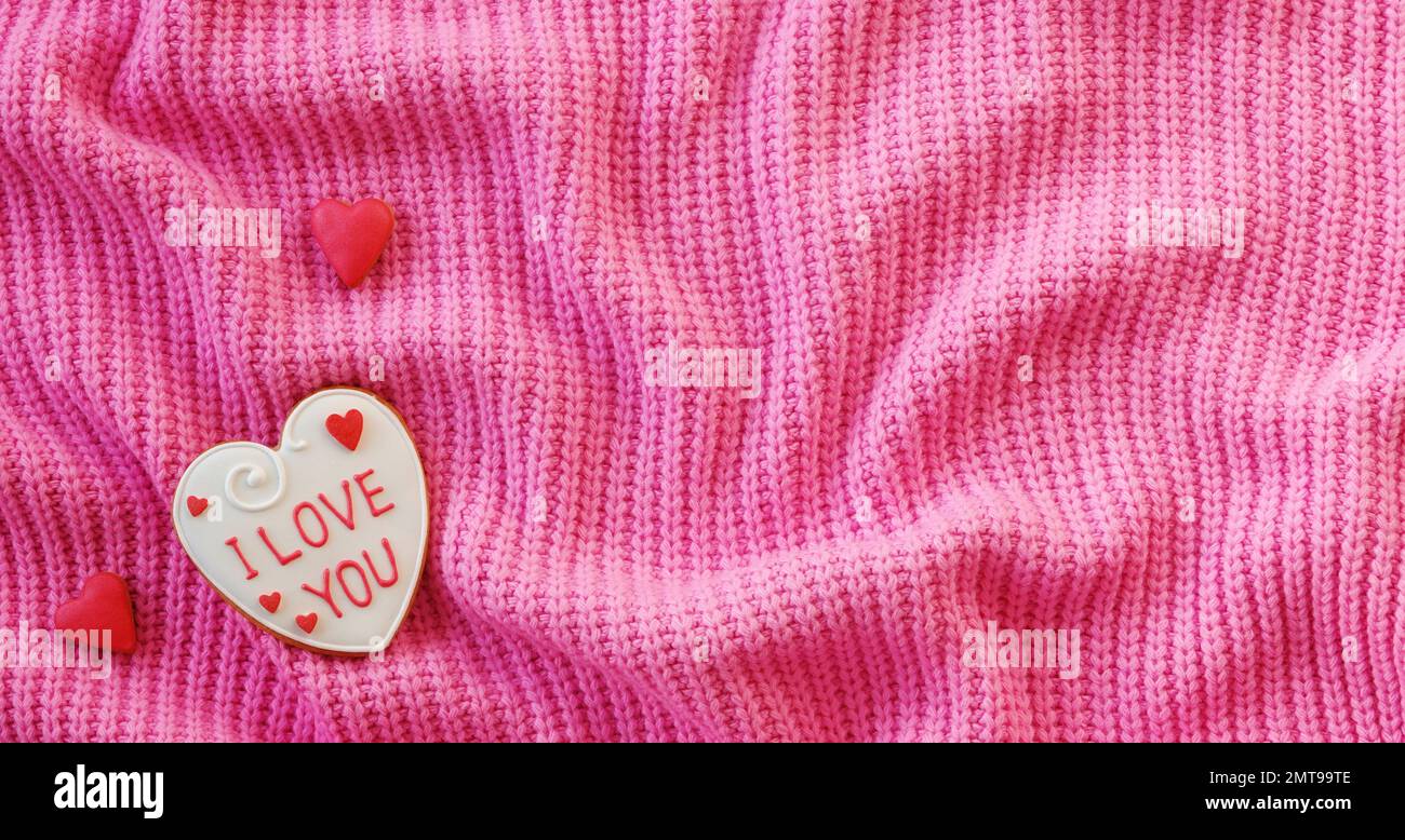 San Valentino sfondo. Biscotti fatti a mano su un tessuto rosa. Pieghe in tessuto. Vista dall'alto Foto Stock