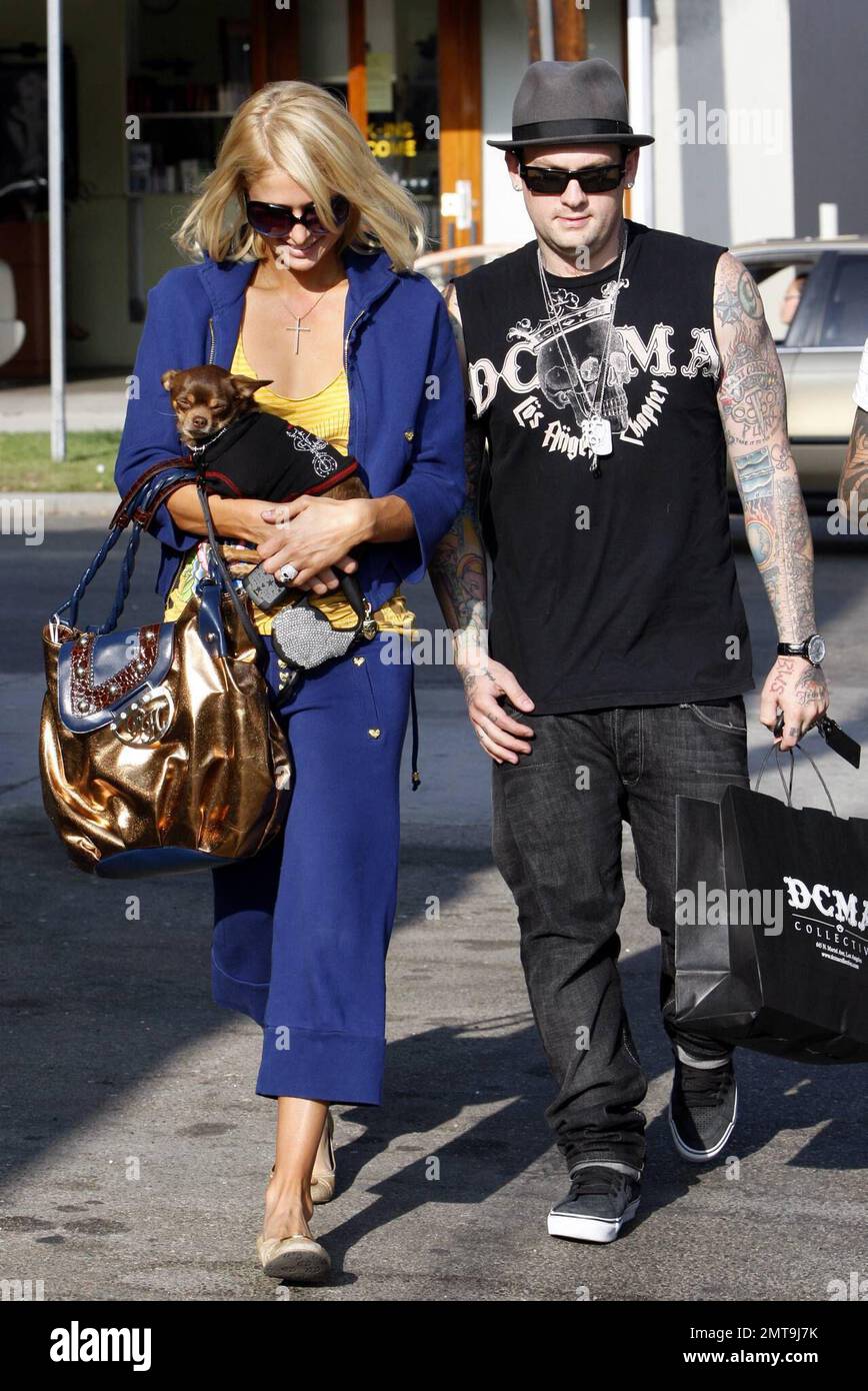 Una di queste cose non è come le altre! Paris Hilton, con il suo piccolo cane al traino, sembra un po' fuori posto con il suo abito colorato e il grande cappello blu mentre lei e il ragazzo Benji Madden fanno una sosta per fare shopping al negozio Benji, il DCMA Collective. Hollywood, California. 5/20/08. Foto Stock