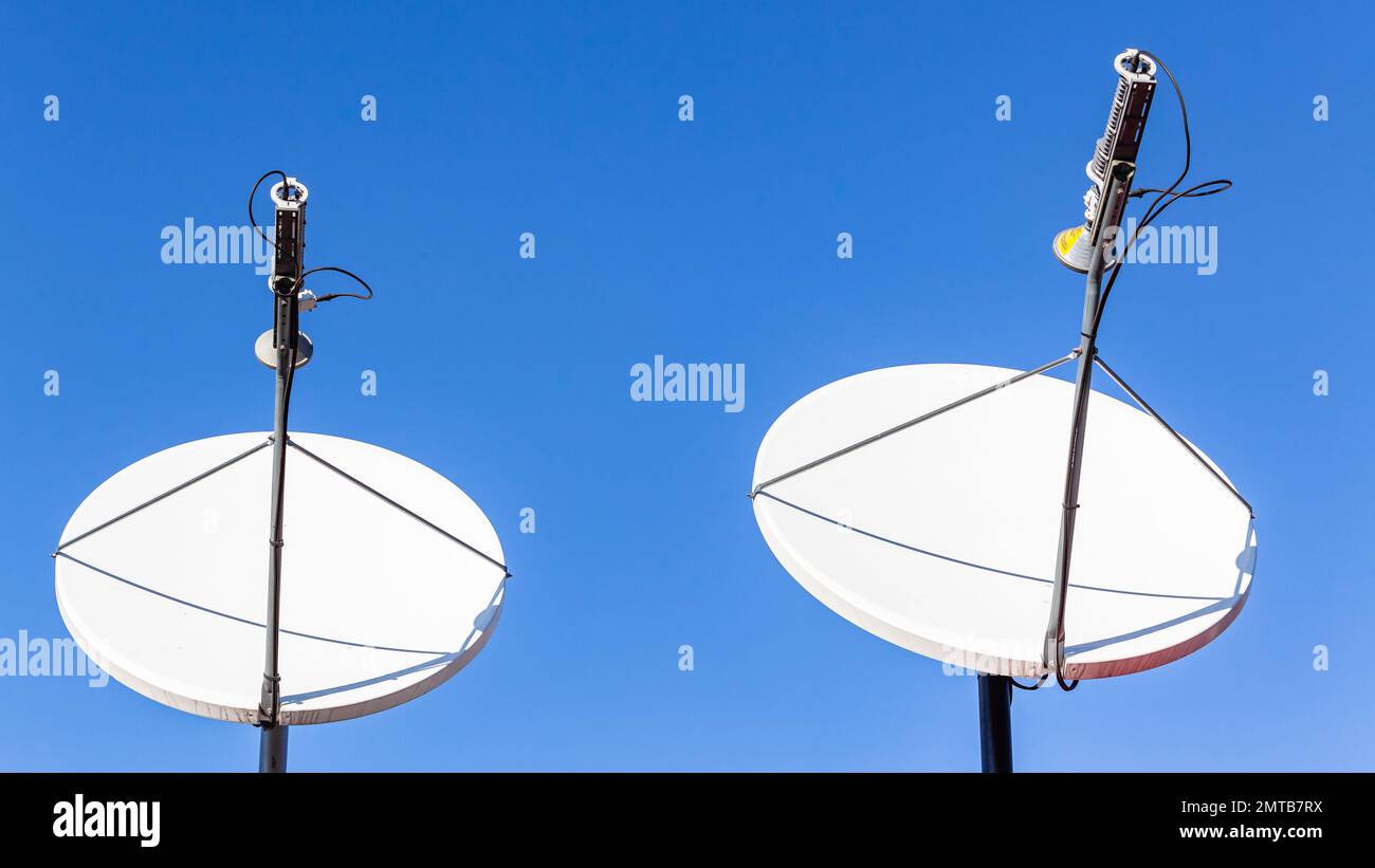 Piatti satellitari due unità vicino al cielo blu in campagna remota Foto Stock