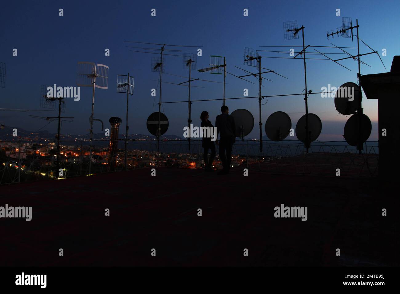 Un paio in cima ad un balcone pieno di antenne e antenne satellitari al crepuscolo a Ercolano, Napoli, Italia. Foto Stock