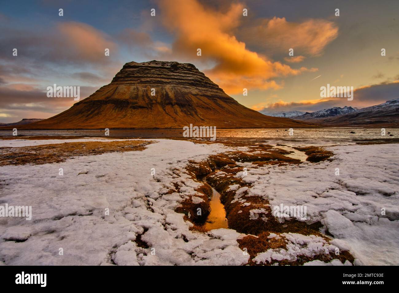 Uno scatto panoramico di una collina rocciosa al tramonto con neve ai piedi Foto Stock