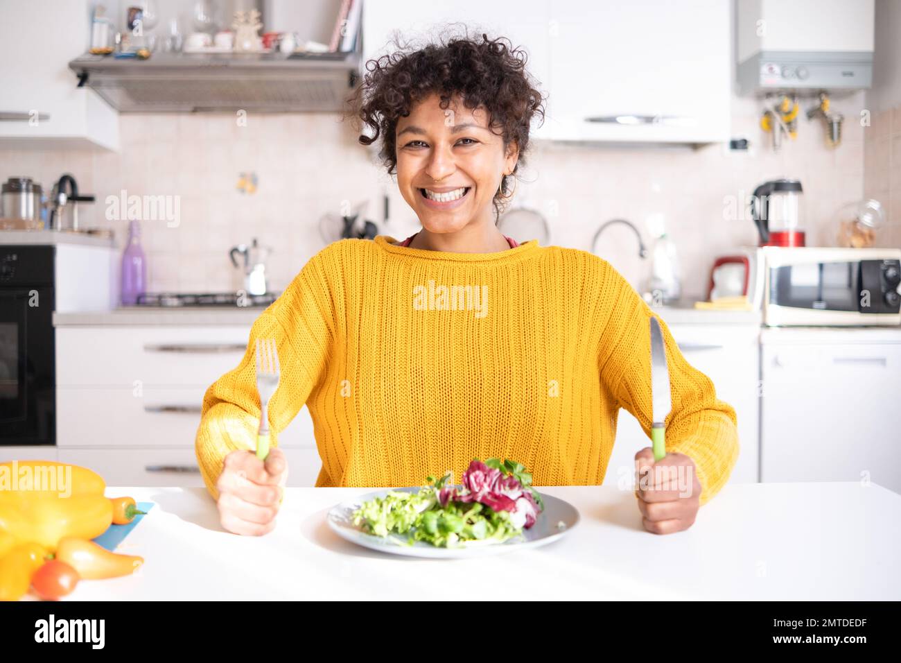 Allegra donna nera che mangia insalata a casa pronta per la dieta Foto Stock