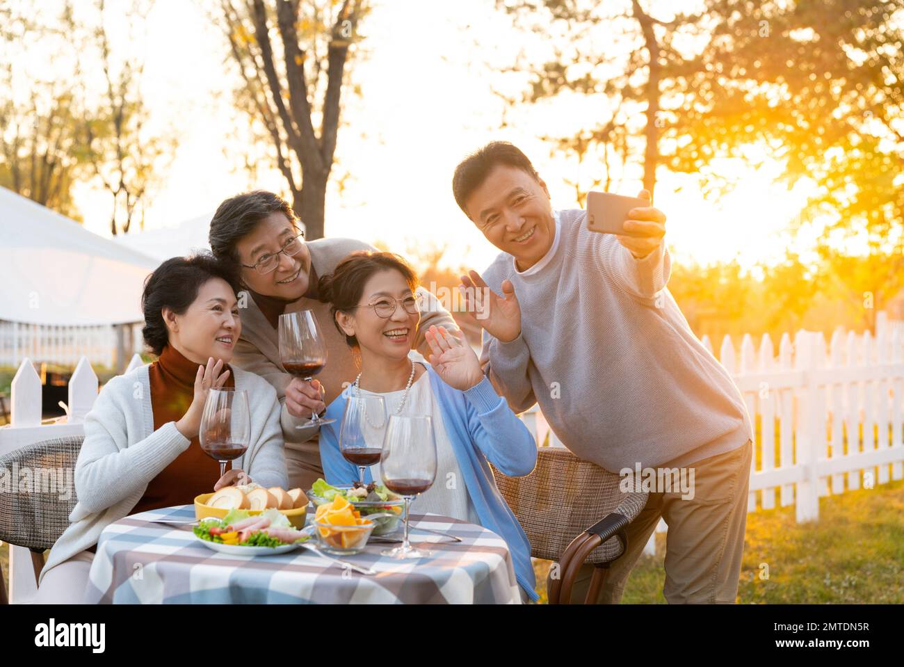 Gli amici di mezza età e vecchi in giardino si bevono le foto al tramonto Foto Stock