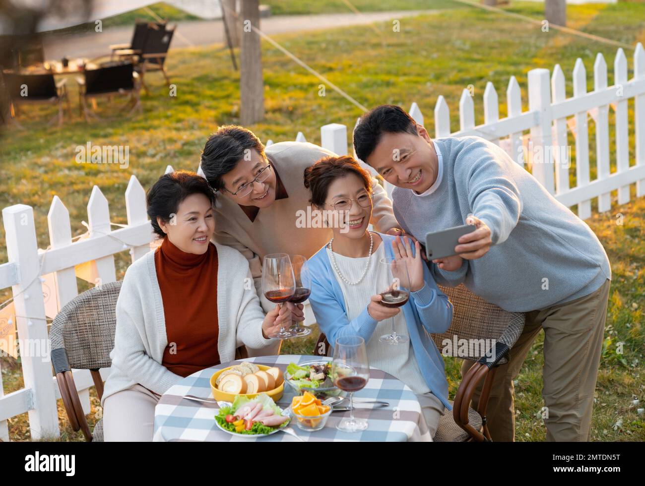 Gli amici di mezza età e vecchi in giardino si bevono le foto al tramonto Foto Stock