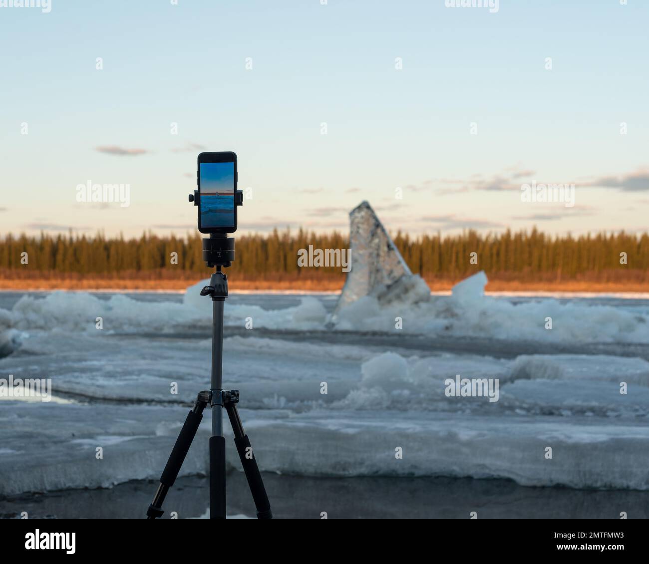 Un telefono cellulare scatta una foto della deriva di ghiaccio primaverile durante il giorno, in piedi su un treppiede con un meccanismo rotante per le riprese panoramiche, contro Foto Stock