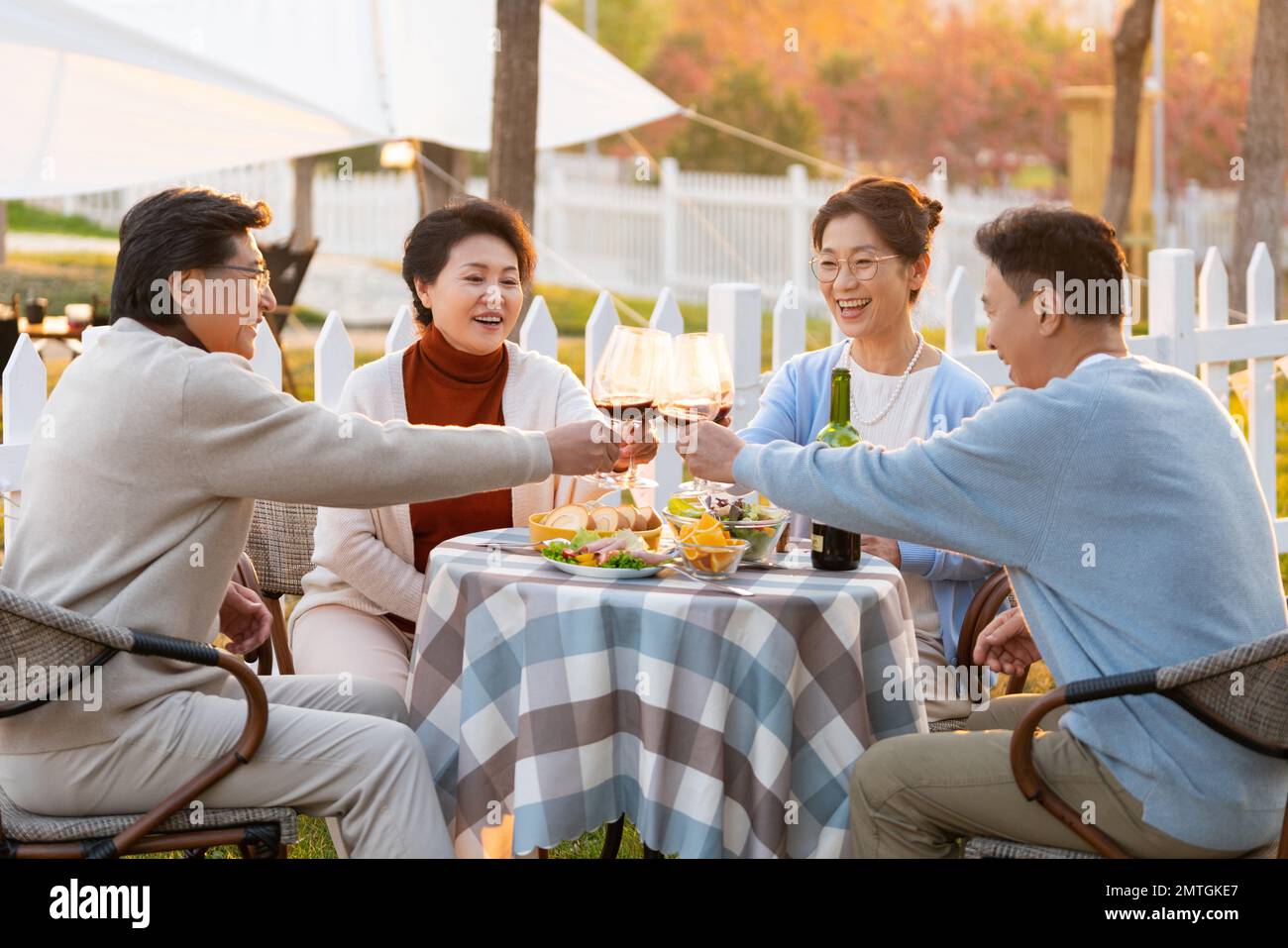 Gli amici di mezza età e vecchi al tramonto nel cortile festa bere chiacchierare Foto Stock