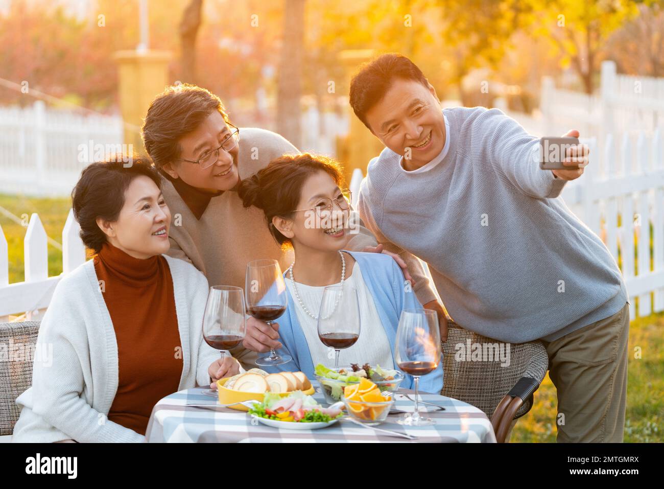 Gli amici di mezza età e vecchi in giardino si bevono le foto al tramonto Foto Stock