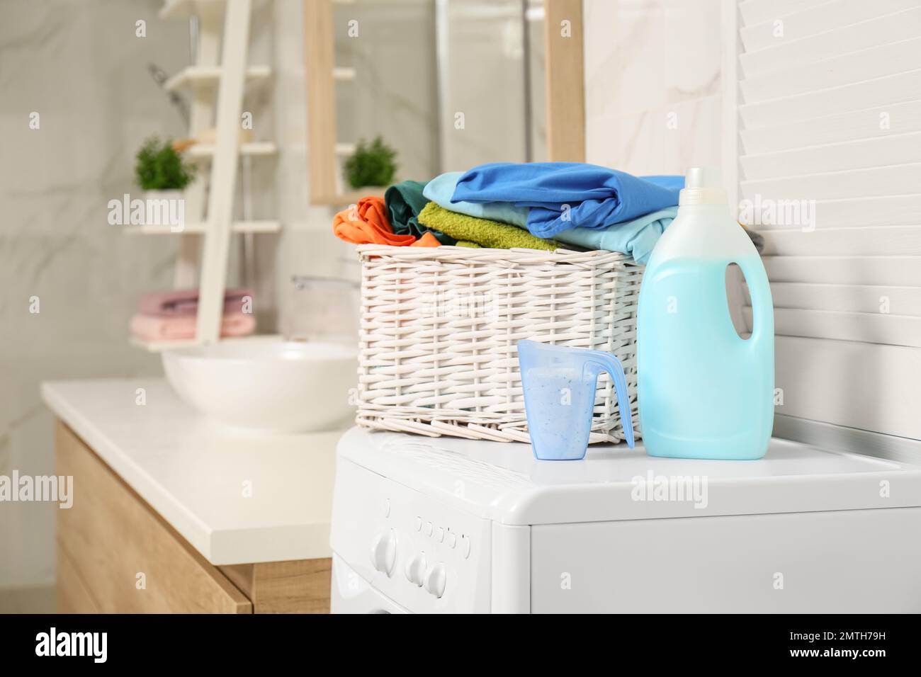 Cesto in vimini con lavanderia e detersivi in lavatrice in bagno Foto stock  - Alamy