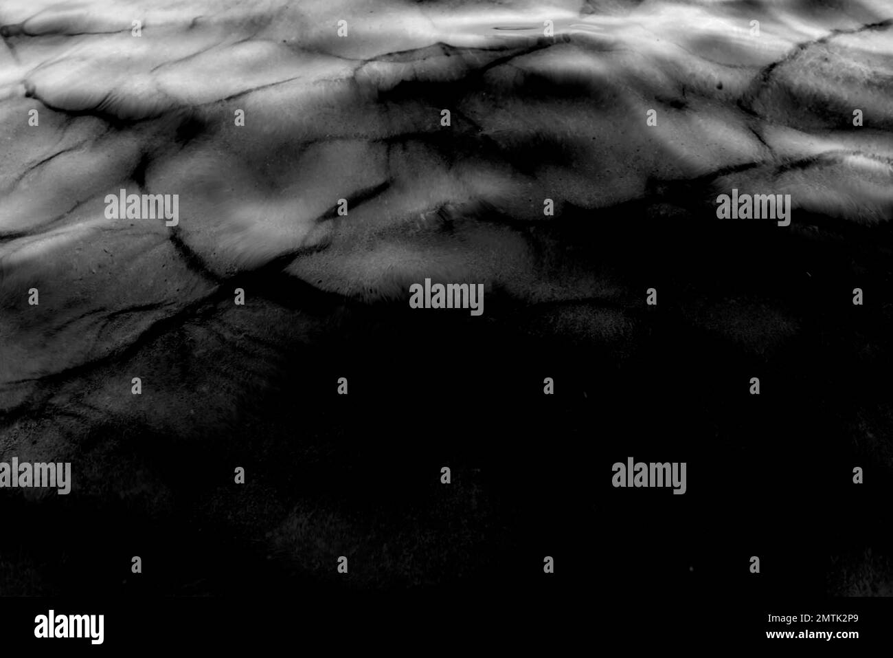 Foto in bianco e nero della texture della superficie d'acqua del movimento delle onde con ombre al buio. Astrazione. Foto Stock