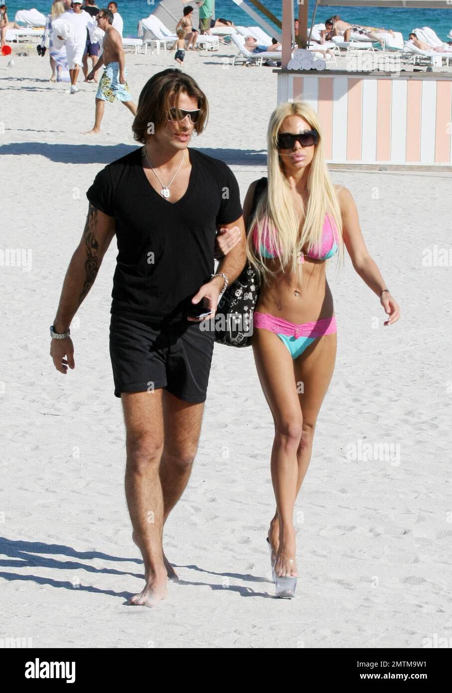 Shauna Sand colpisce la spiaggia con il marito. La coppia si baciò e si baciò, ottenne tatuaggi all'henné e Shuna eseguì il suo bizzarro bikini cambiante sulla spiaggia, Miami Beach, FL, 01/23/09. Foto Stock