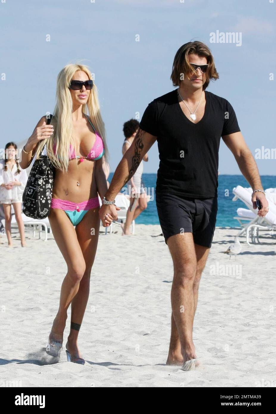 Shauna Sand colpisce la spiaggia con il marito. La coppia si baciò e si baciò, ottenne tatuaggi all'henné e Shuna eseguì il suo bizzarro bikini cambiante sulla spiaggia, Miami Beach, FL, 01/23/09. Foto Stock