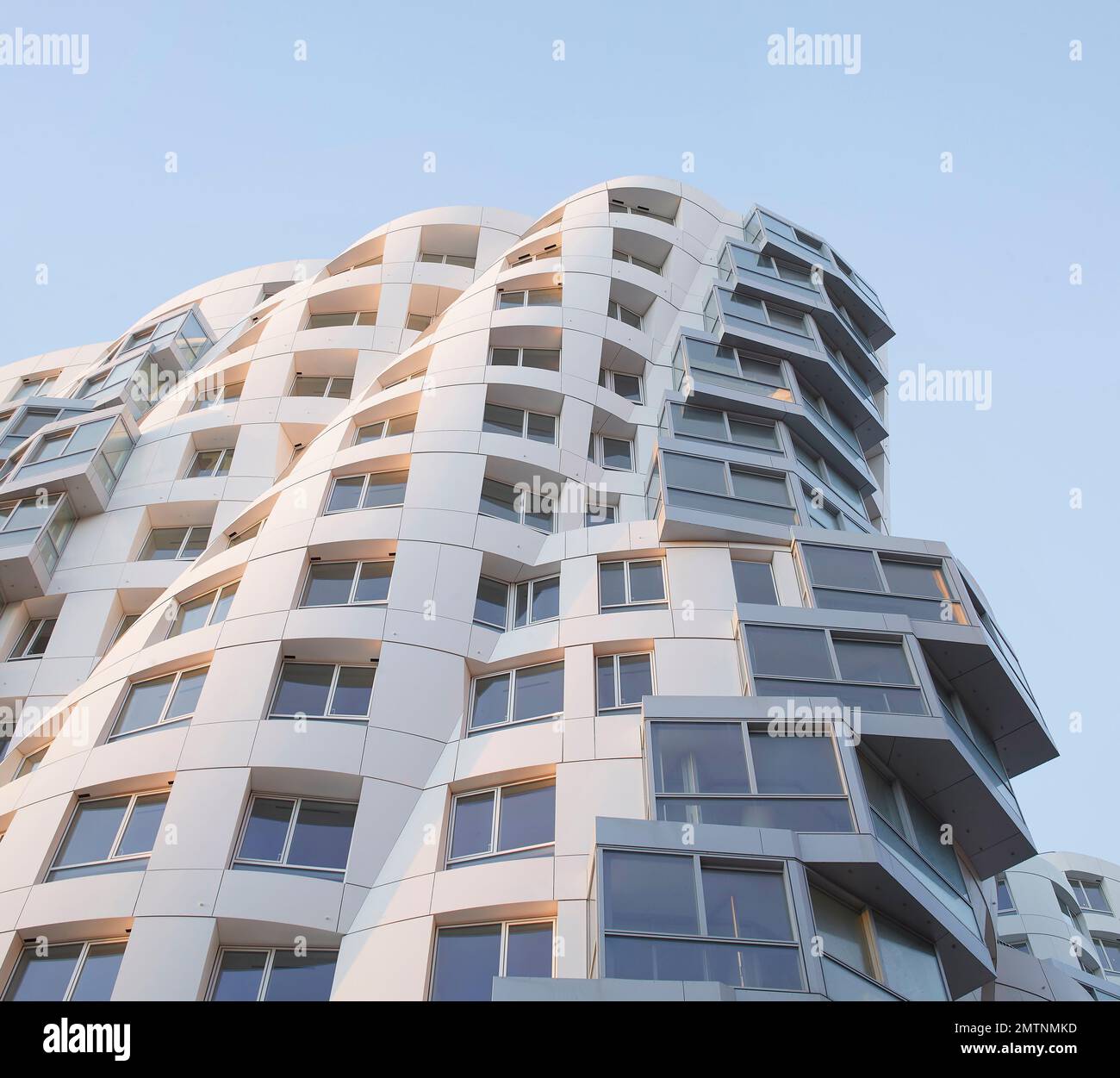 Guardando verso il cielo lungo la facciata bianca. Prospect Place Battersea Power Station Frank Gehry, Londra, Regno Unito. Architetto: Frank Gehry, 2022. Foto Stock