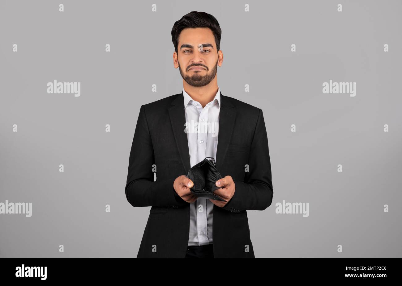 Giovane uomo d'affari del Medio Oriente in tuta che mostra il portafoglio vuoto alla fotocamera Foto Stock