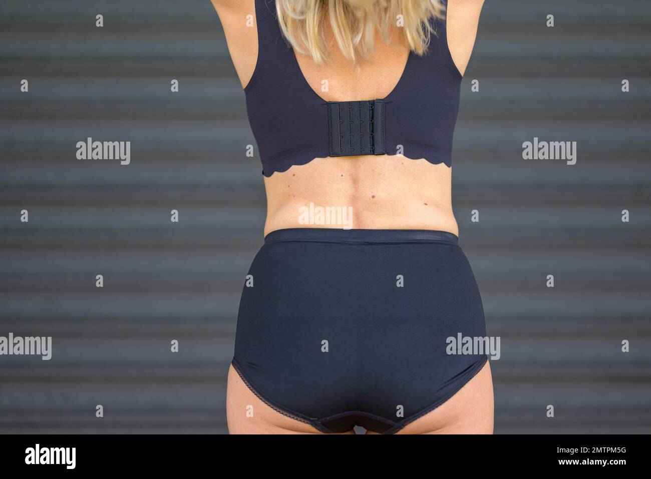 Vista posteriore di una donna bionda di mezza età in un reggiseno nero Foto Stock