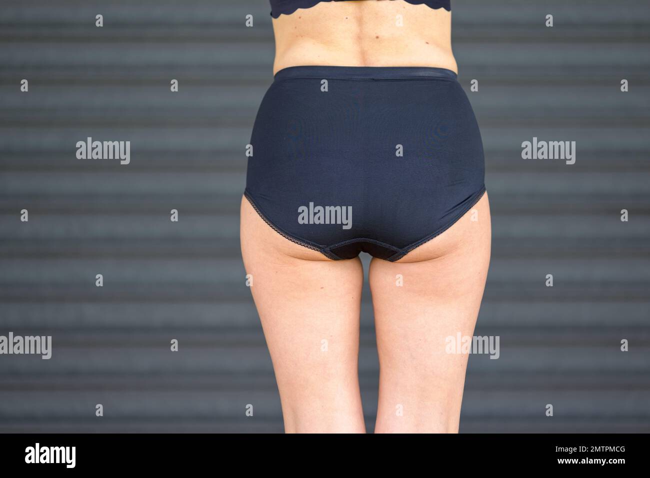 Vista posteriore di una donna bionda di mezza età in un reggiseno nero e pantaloni neri Foto Stock