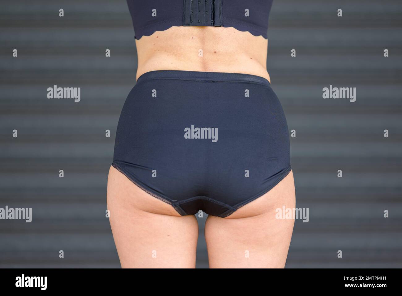 Vista posteriore di una donna bionda di mezza età in un reggiseno nero e pantaloni neri Foto Stock