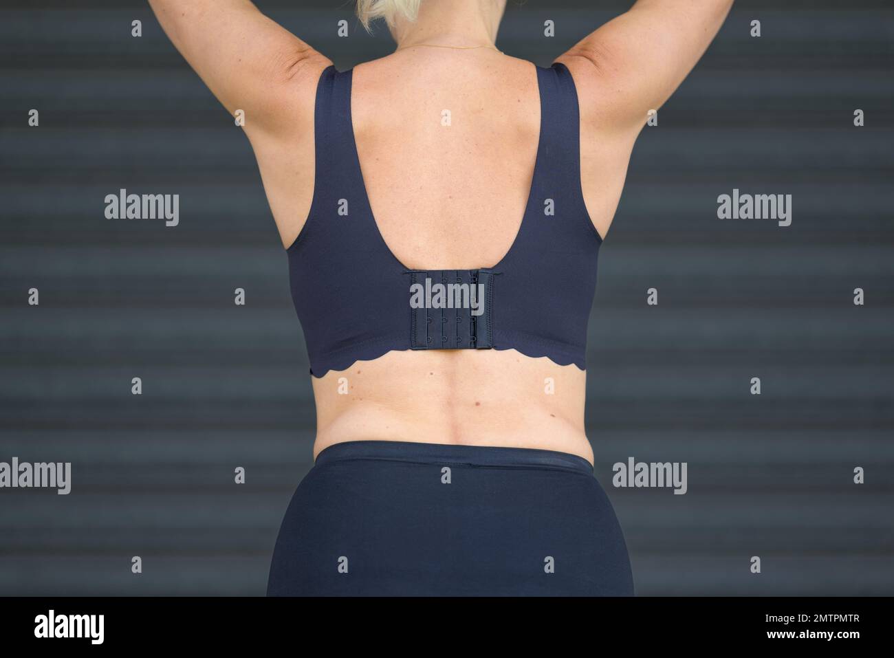 Vista posteriore di una donna bionda di mezza età in un reggiseno nero e pantaloni neri Foto Stock
