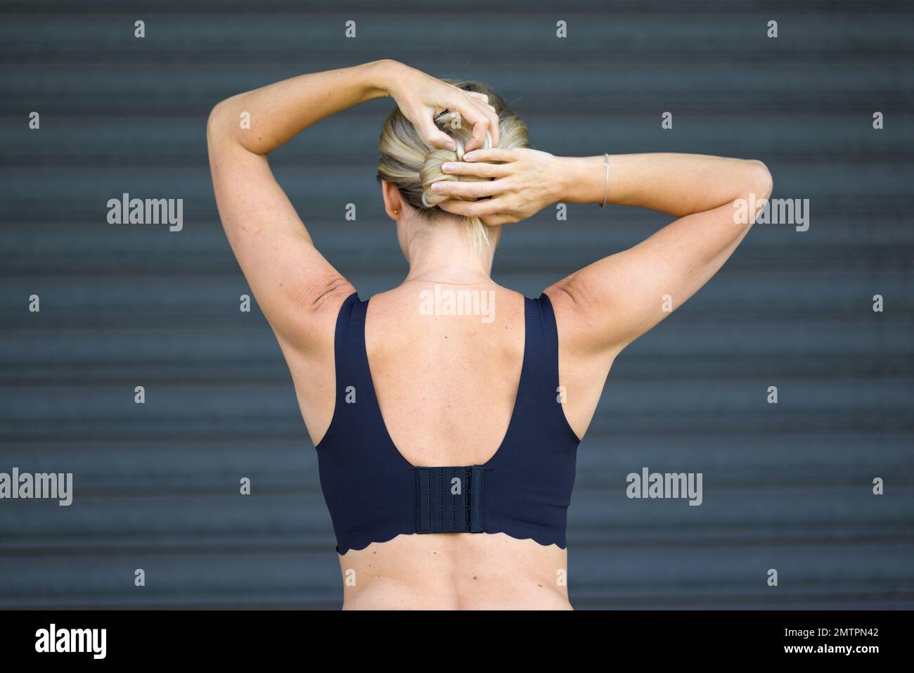 Vista posteriore di una donna bionda di mezza età in un reggiseno nero Foto Stock