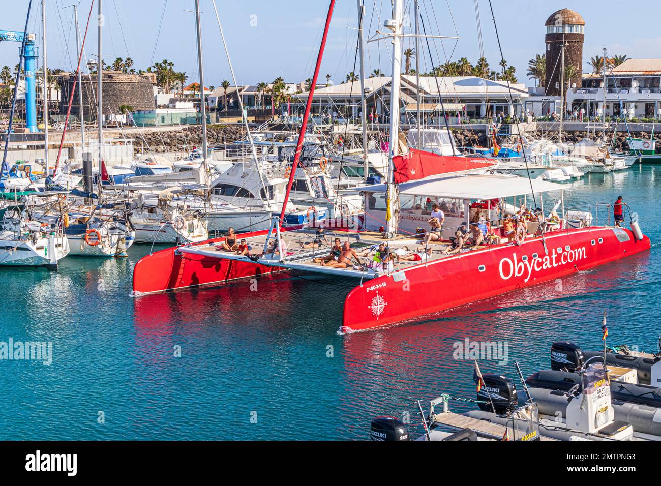 I turisti a bordo del catamarano Obycat Experience lasciano il porto di Caleta de Fuste sulla costa orientale dell'isola delle Canarie di Fuerteventura, Spagna Foto Stock