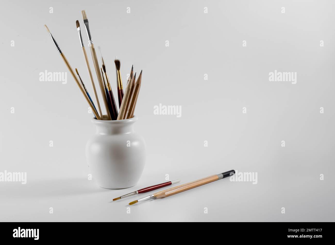 gli artisti di acquerello pennellano e disegnano matite in un vaso isolato su uno sfondo bianco Foto Stock