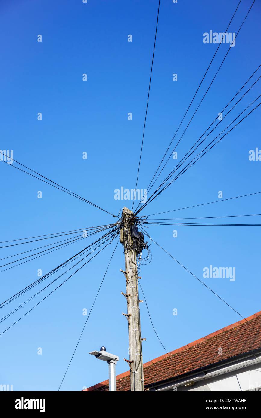 Cavi telefonici e scatola di derivazione sulla parte superiore di un palo di legno contro il cielo blu Foto Stock