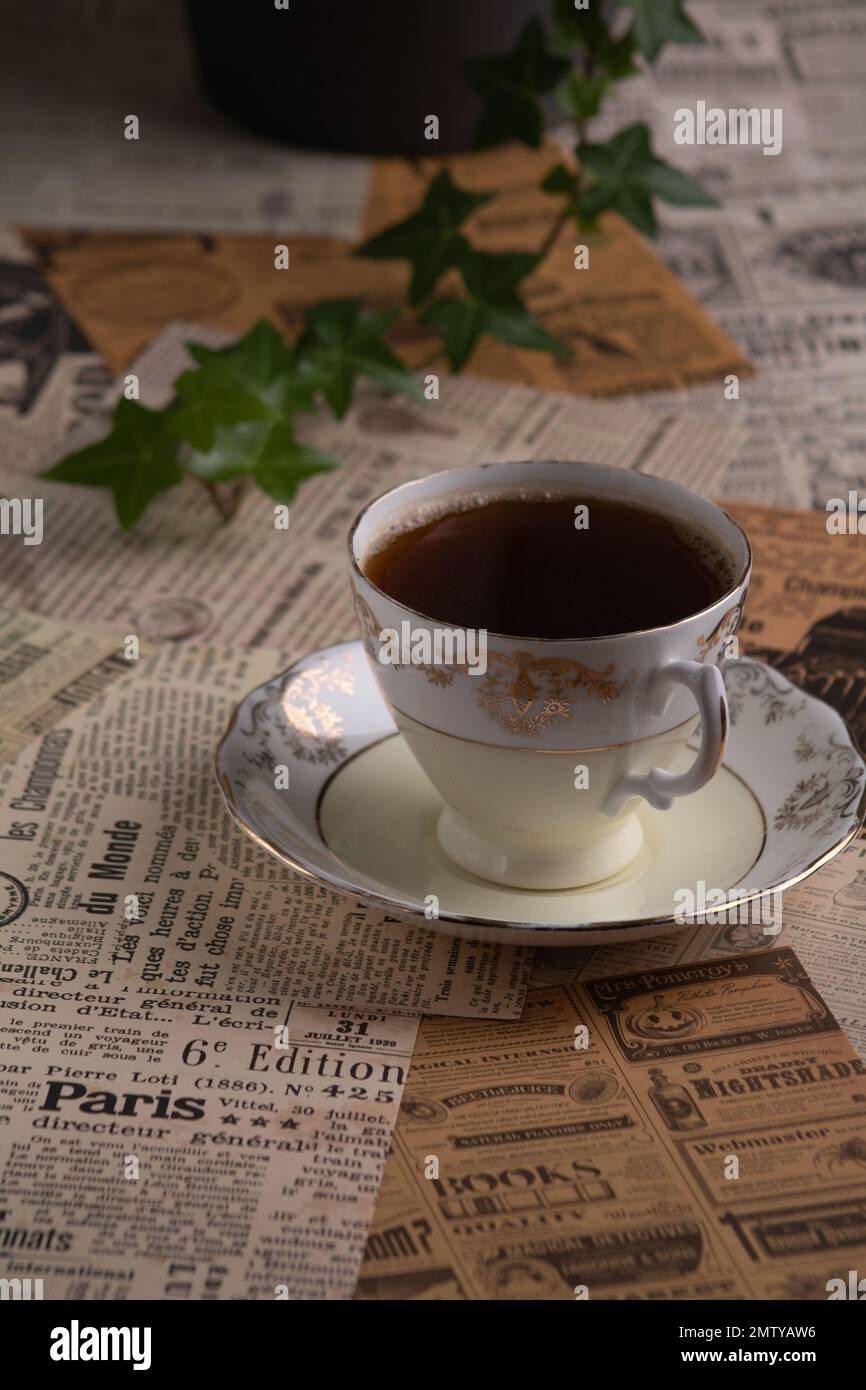 foto di una vecchia tazza di caffè su un piattino sullo sfondo di vecchi ritagli di giornale Foto Stock