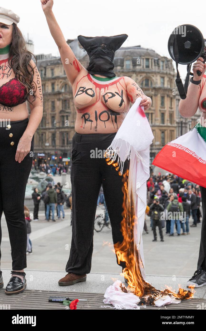 Londra, Inghilterra, Regno Unito 01/02/2023 le donne hanno nudo i loro seni e corpi per un Riot globale del corpo per la libertà di vita delle donne sul giorno di no Hijab. Le donne si trovavano sulle scale di Trafalgar Square con slogan sul loro corpo e hijab simbolicamente bruciati Foto Stock