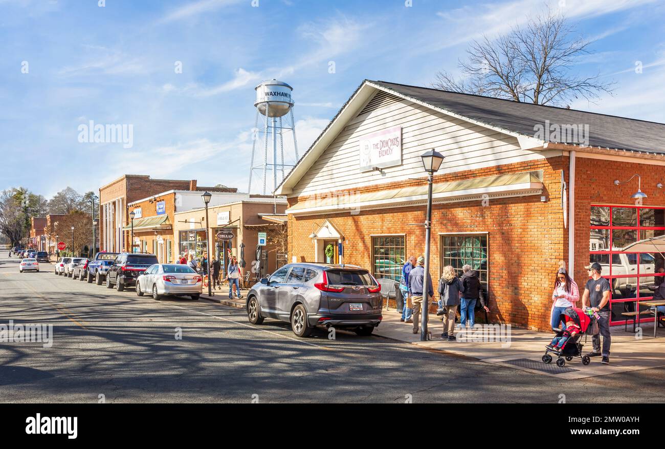 WAXHAW, NC, USA-28 GEN 2023: North Main Street piena di persone in una giornata invernale soleggiata. Vista diagonale con torre dell'acqua dietro la fabbrica di birra Dream Chaser's. Foto Stock WAXHAW, NC, USA-28 GEN 2023: North Main Street piena di persone in una giornata invernale soleggiata. Vista diagonale con torre dell'acqua dietro la fabbrica di birra Dream Chaser's. Foto Stock