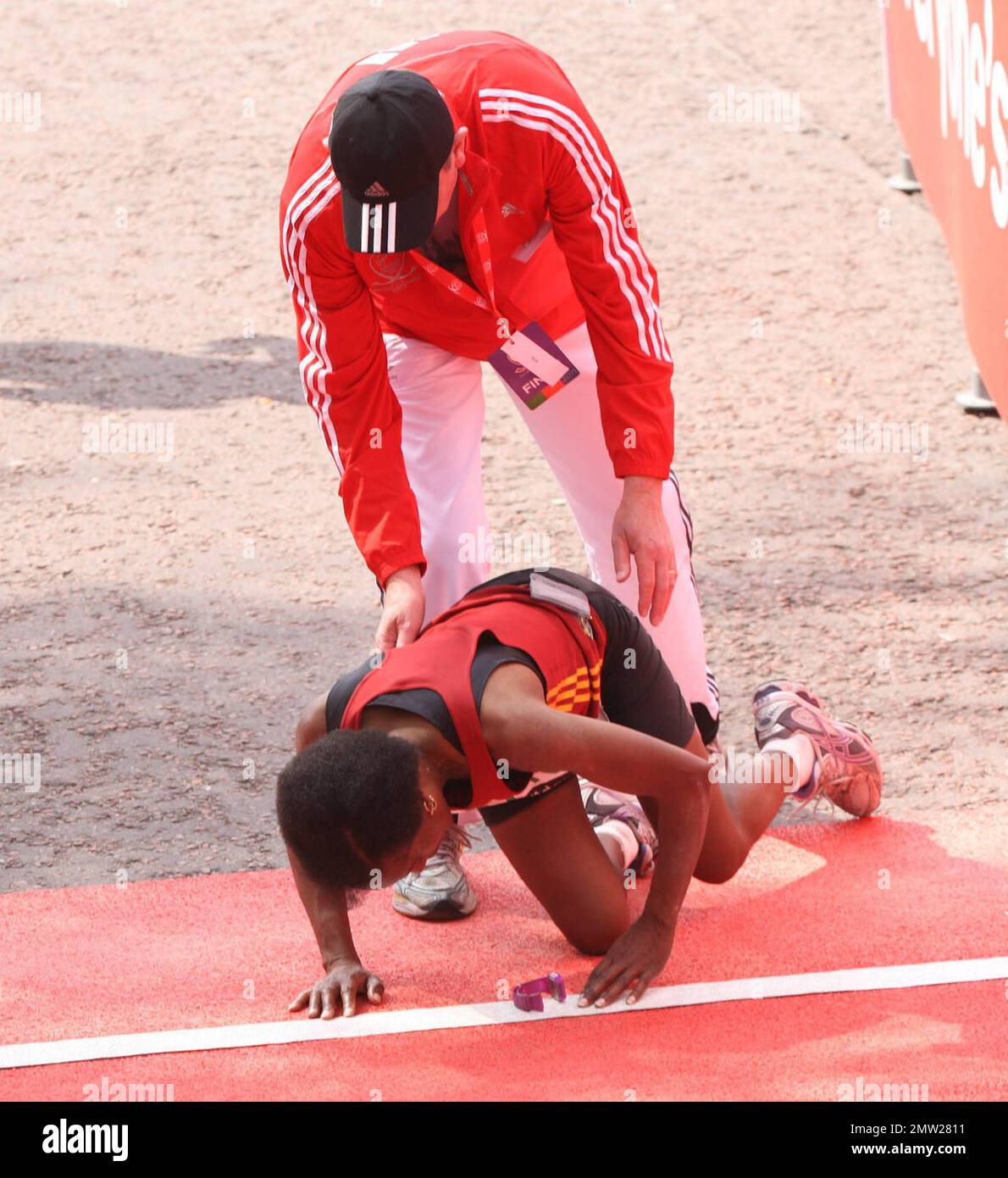 Un corridore cade al traguardo dopo la 2011 Virgin London Marathon. Londra, Regno Unito. 04/17/11. Foto Stock