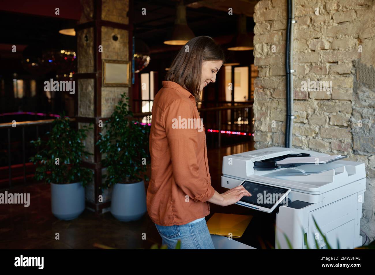 Giovane dipendente che lavora alla stampante in un ufficio di coworking Foto Stock
