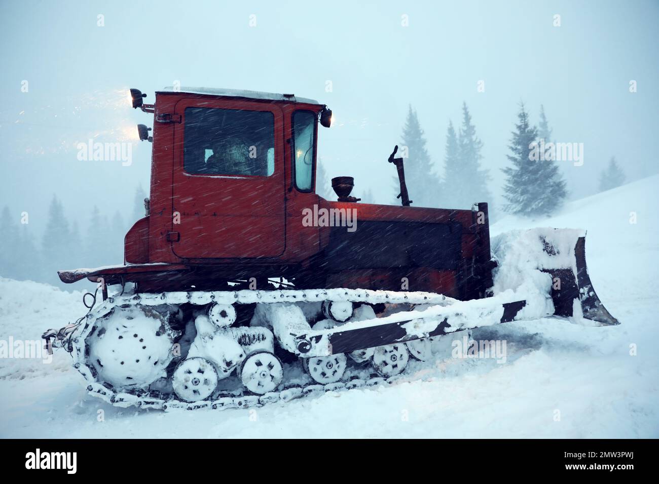 Il trattore pulisce la strada in caso di nevicate. Stagione invernale Foto Stock