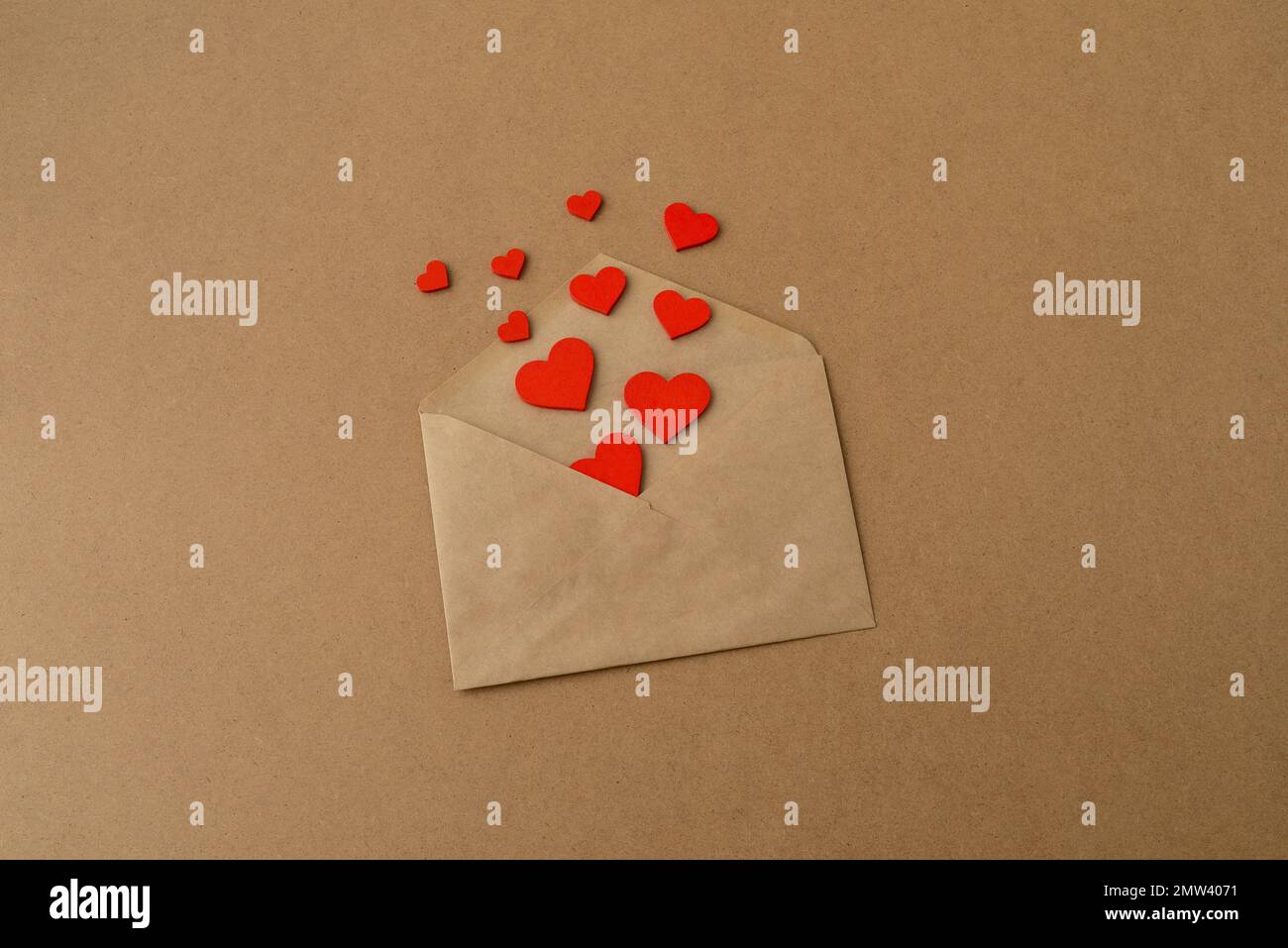 San Valentino. Busta con cuori rossi su sfondo di carta kraft. Febbraio 14th concetto di vacanza Foto Stock