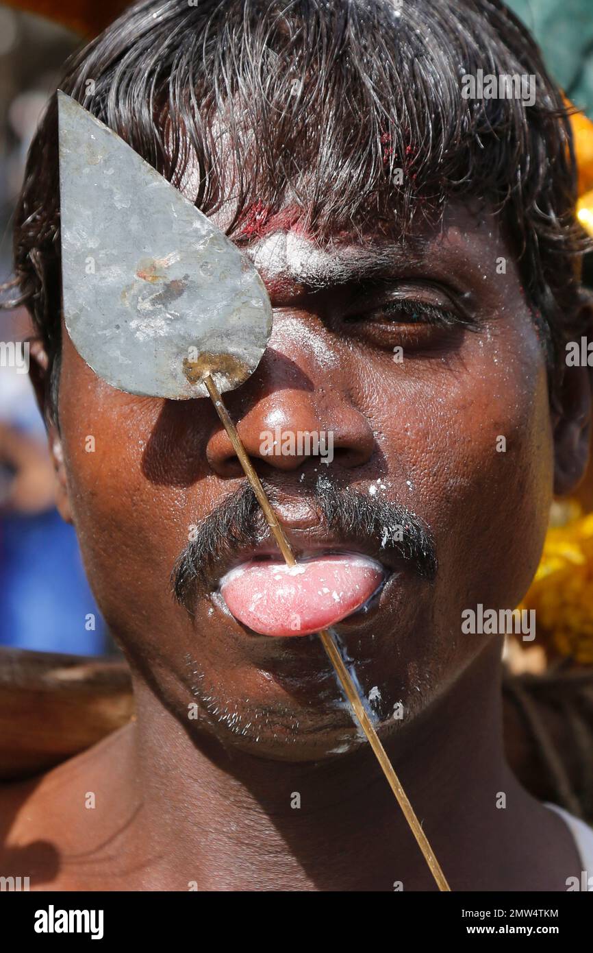 An Indian Tamil Hindu devotee, with his tongue pierced with a metal rod, participates in a religious procession during Panguni Uthiram festival in Ahmadabad, India, Sunday, April 9, 2017. The festival is observed in the Tamil month of Panguni and is celebrated in honor of the Hindu God Murugan where devotees make offerings to lord Murugan with sacrificial feats which they believe keeps them away from evil spirits. (AP Photo/Ajit Solanki) Foto Stock