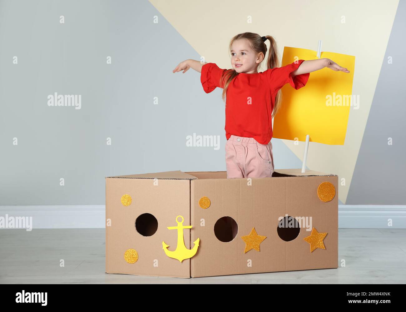 Carino bambino che gioca con la nave di cartone vicino alla parete di  colore Foto stock - Alamy