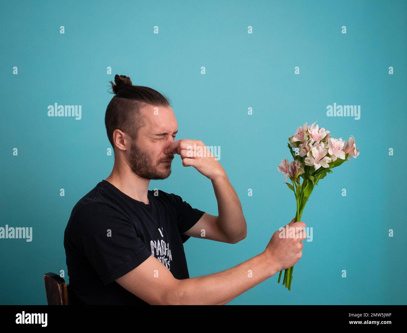 Uomo bianco con allergia pollena da fiori di tenuta su uno sfondo turchese Foto Stock